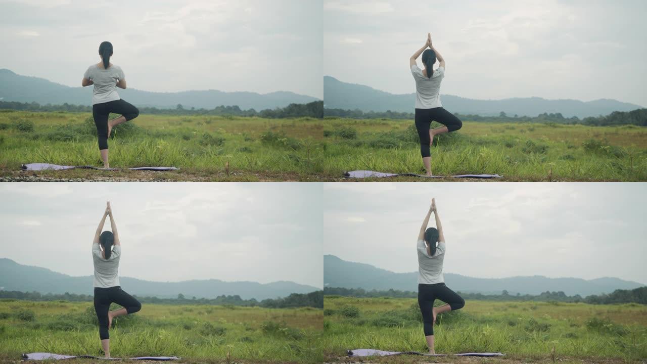 美丽的亚洲女性做瑜伽练习冥想，在日出时在山景中表演精神瑜伽姿势。
