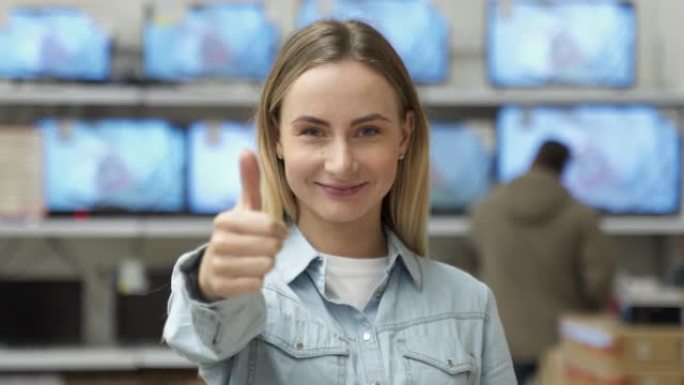 一个迷人的女人微笑着竖起大拇指的特写肖像。关于工作电视的背景