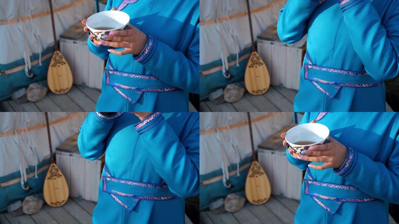 穿着亚洲服装的女人在蒙古包附近喝茶