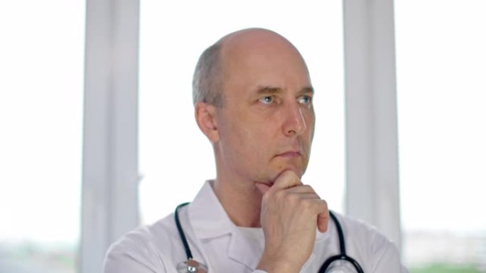 严肃的中年医生用手站在下巴上思考诊断的肖像