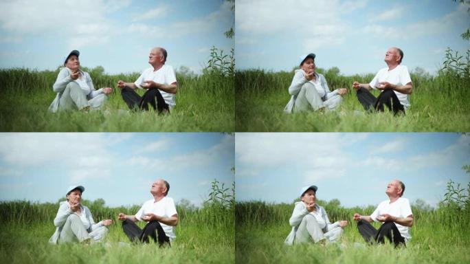 健康的生活方式在老年，一对热爱运动生活方式的已婚老年夫妇在户外进行体育锻炼坐在温暖的阳光明媚的绿色草