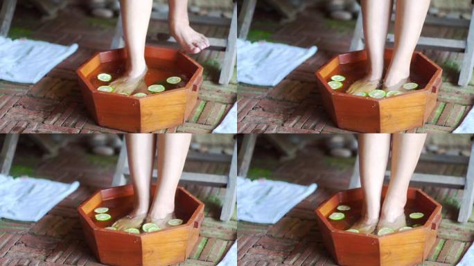 女人的脚浸入木碗中的草药水中，以在水疗前放松身心。