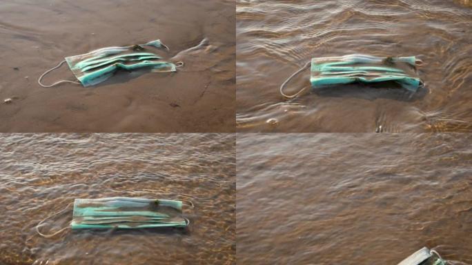 传染性废物-海滩上水中的医用口罩。自新型冠状病毒肺炎以来的海洋污染