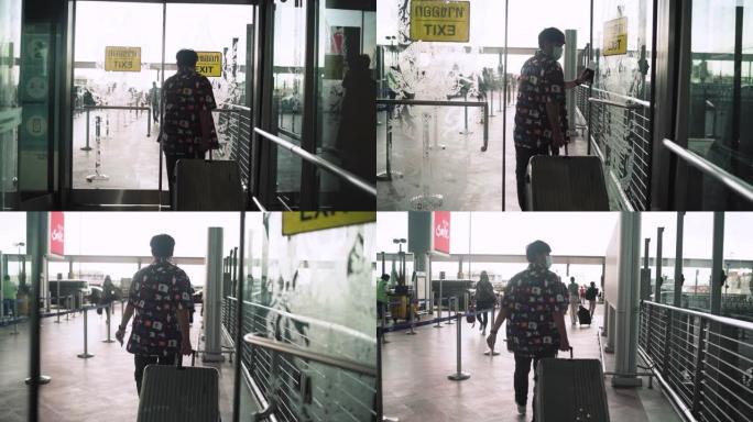 亚裔男子提着灰色行李箱，前往登机柜台航空公司机场