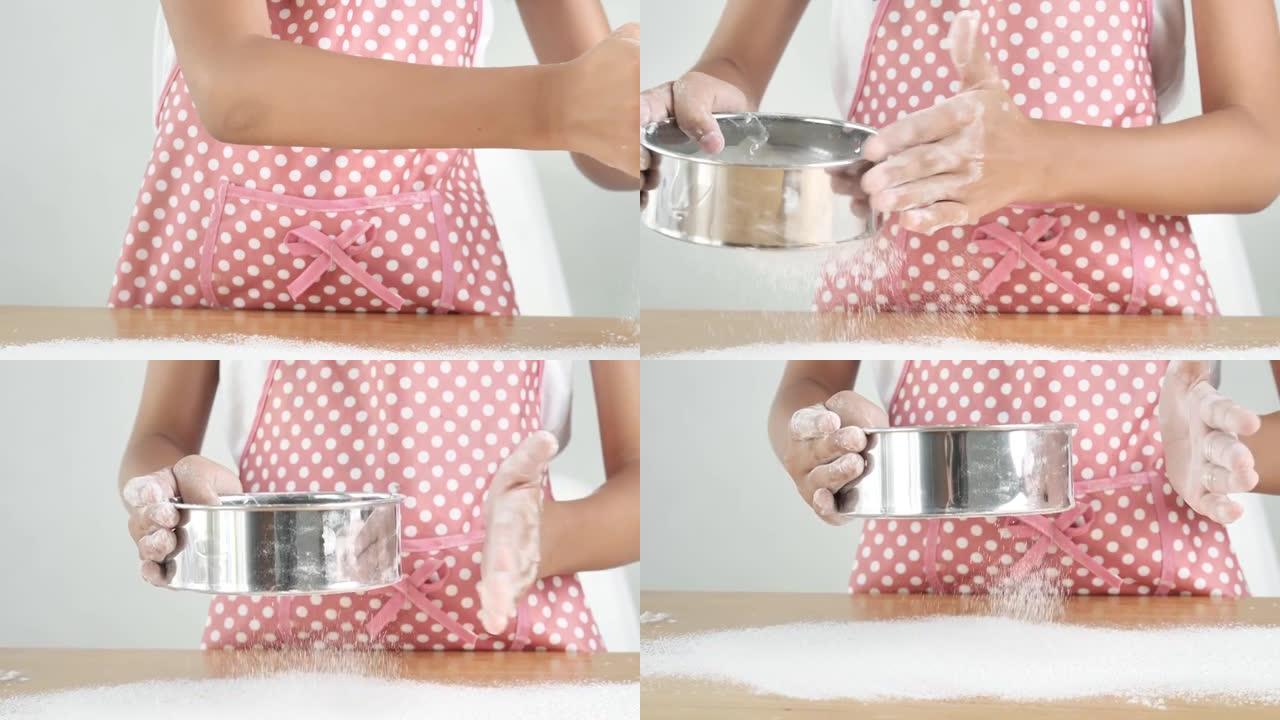 双手将面粉粉落在桌子的顶部，使蛋糕加工。
