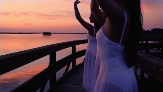 穿着长裙的芭蕾舞演员在日落时在桥上表演舞蹈