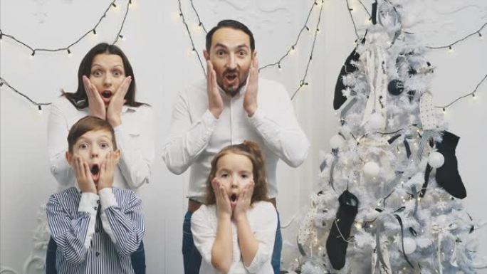 在新年背景下，年轻父母和他们的孩子的Slowmotion 4k视频，张开嘴，双手放在脸颊上，用恐怖的