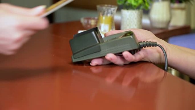 客户通过信用卡支付订单。在咖啡馆，餐厅，商店中，女性双手握着终端的特写镜头。卖家、服务员、咖啡师接受