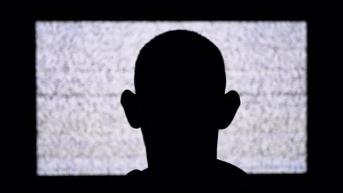 一名匿名男子头部的剪影正在观看白色静电噪音和电视干扰
