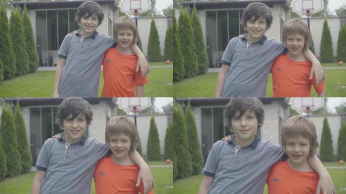 两个快乐男孩在户外摆姿势的肖像。微笑的高加索兄弟或朋友拥抱并看着相机。童年和友谊的概念