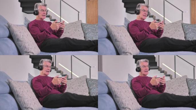 沙发上戴着耳机的老人通过蓝牙智能手机听音乐