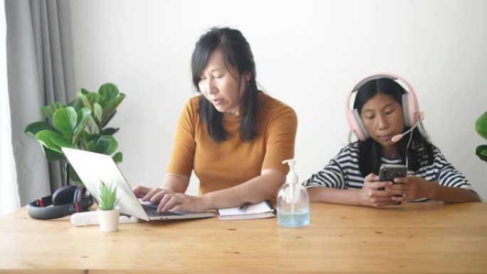 亚洲母亲和她的女儿在新型冠状病毒肺炎期间在家工作。