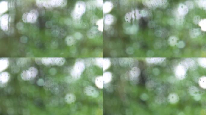 玻璃窗外面雨滴的特写镜头。绿色背景上流下的雨滴。