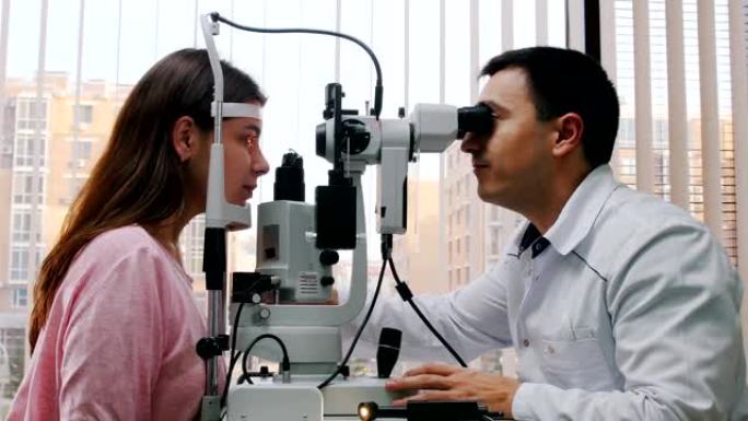 眼科治疗-医生用大型验光机检查年轻女性的视力-带百叶窗的全景窗户的宽敞橱柜