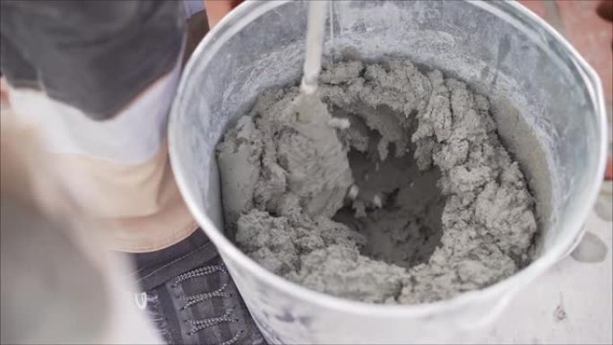 建筑商将砂浆与砖混合。在桶中混合溶液。