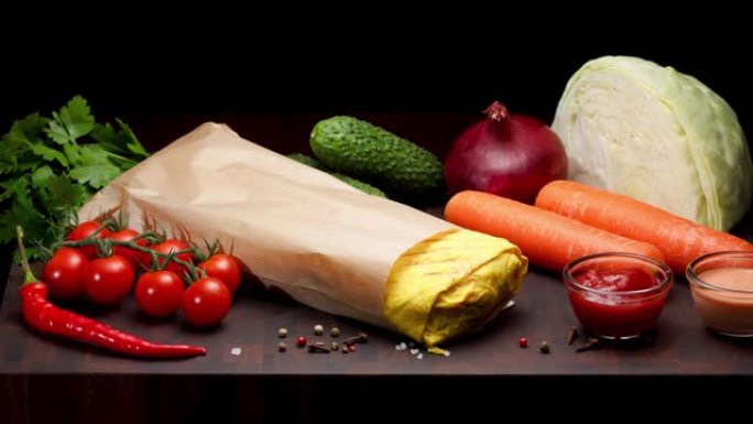 黄色沙瓦玛在纸包装上，黑色背景上有蔬菜和调味料。