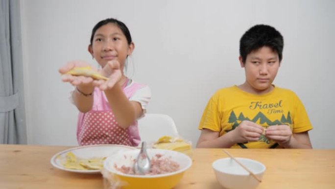快乐亚洲儿童在家一起包饺子，生活理念。