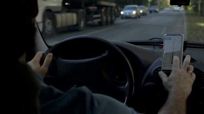 一名男子上车，打开智能手机上的导航器
