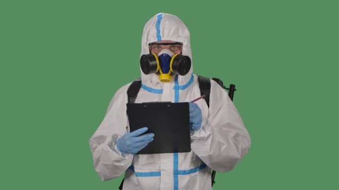 穿着防护服，护目镜，手套和呼吸器的男人的肖像拿着一个文件夹，并标记了潜在的危险场所。绿色屏幕，色度键