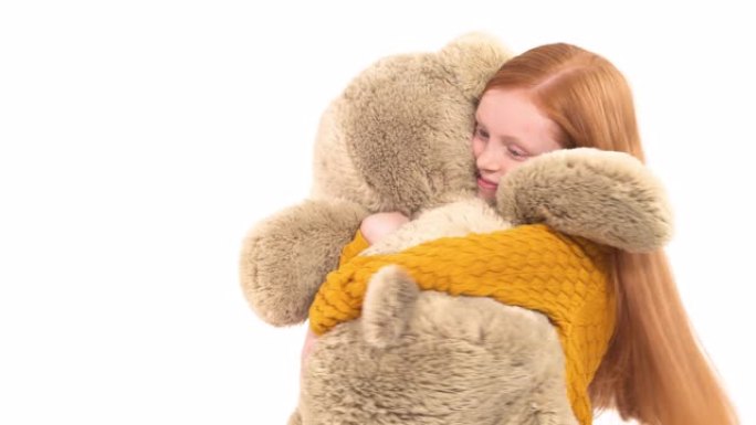 一个迷人的小女孩与她巨大的泰迪熊玩耍的特写镜头。孤立，在白色背景上。快乐童年理念