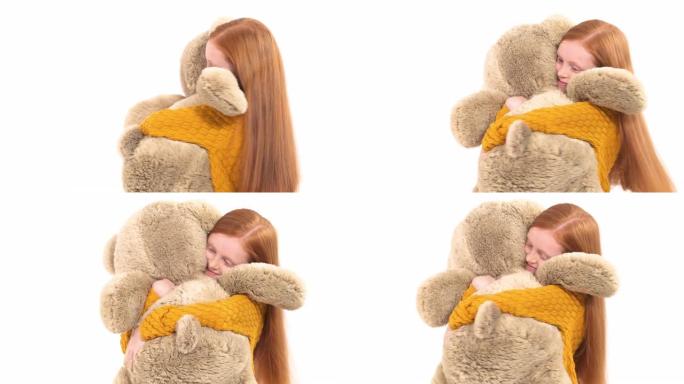 一个迷人的小女孩与她巨大的泰迪熊玩耍的特写镜头。孤立，在白色背景上。快乐童年理念