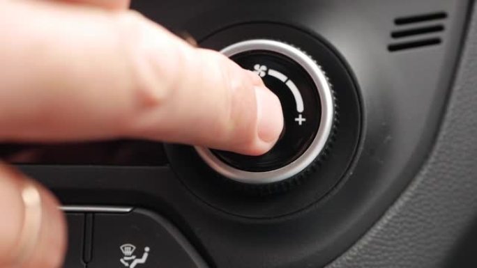 按下按钮打开汽车空调的特写镜头。男人的手转动按钮