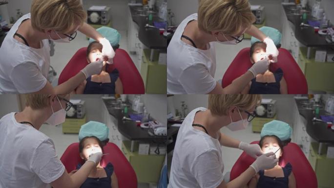 儿科牙医使用倾斜的镜子和探针来探索牙齿表面的龋齿