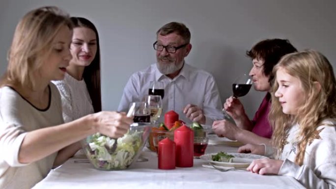 家人围坐在桌子旁，在家庭晚餐时吃饭，交流和娱乐。家庭在厨房里在家敬酒