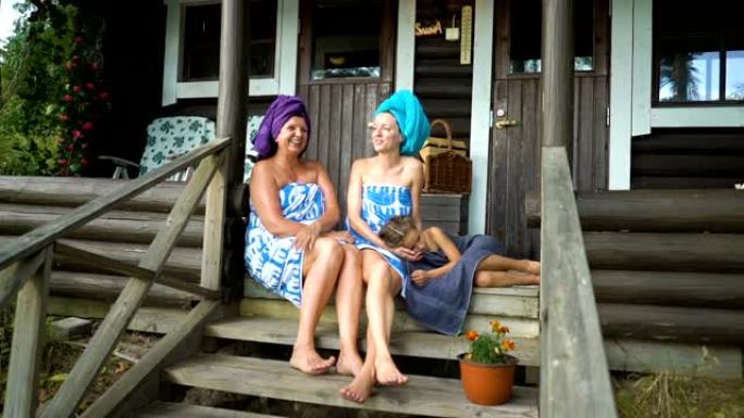 三个女性桑拿爱好者在传统芬兰桑拿浴室的门廊上享受新鲜空气