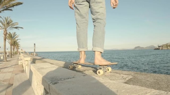 穿着蓝色牛仔裤的小男孩在码头上赤脚滑冰，背景是大海