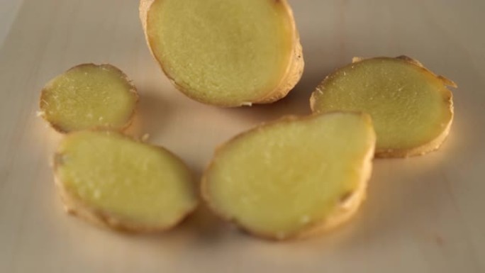 多汁成熟的姜根切片在木质表面上旋转。