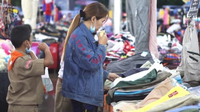 慢动作: 亚洲母婴在市场摊位上买衣服