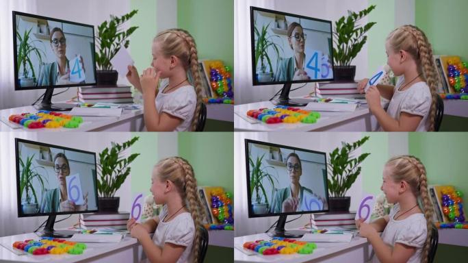 远程教育在大流行期间，漂亮的小女孩坐在家里拿着电脑给老师看学校在线课程的卡片