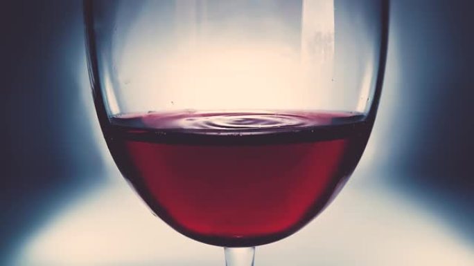 创意微距慢动作视频红酒在一杯和一滴落的酒。酒杯上慢慢落下的酒滴特写。旧复古垃圾复古风格，柔和褪色。