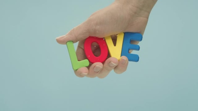 拼出五颜六色的塑料字母的 “爱” 一词握在手中，淹没在水中。