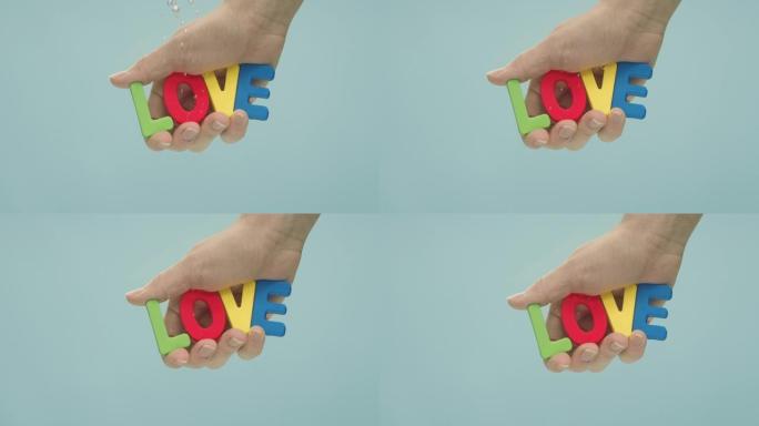 拼出五颜六色的塑料字母的 “爱” 一词握在手中，淹没在水中。