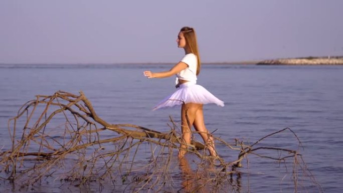 穿着芭蕾舞短裙和t恤的女人在水中的树枝附近跳芭蕾舞