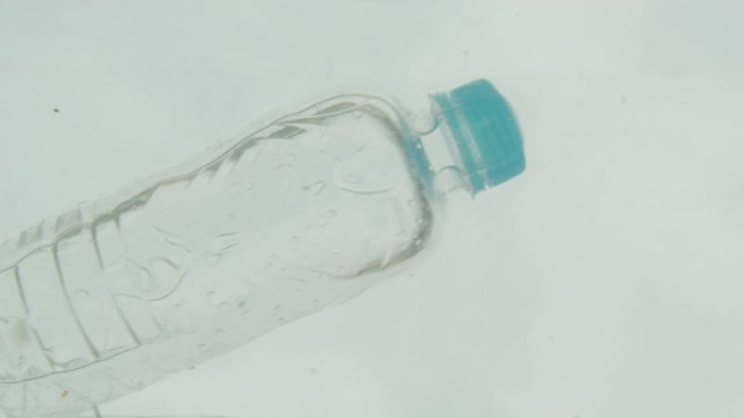 男性手在海水中扔塑料瓶的特写镜头。全球污染问题