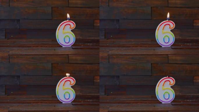 乡村木质背景上点燃的6号生日蜡烛。