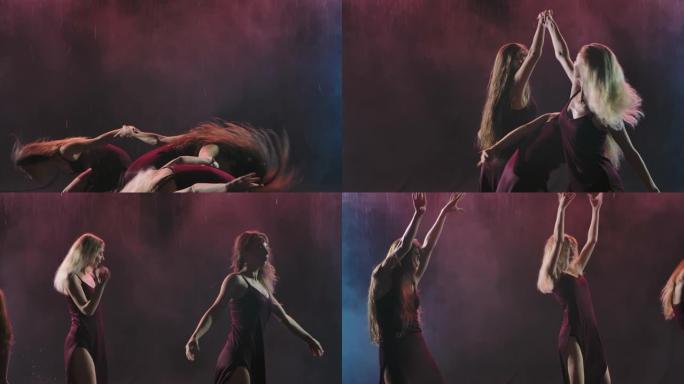 一群穿着长裙的女人在烟熏的背光工作室里跳舞现代舞蹈。慢动作。特写