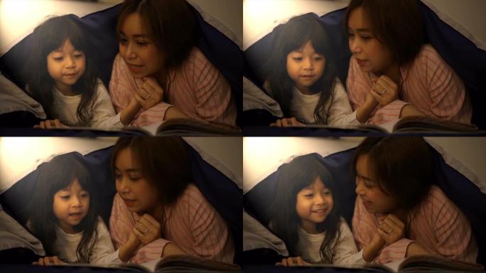 母亲在睡前定期在毯子下给女儿讲故事。