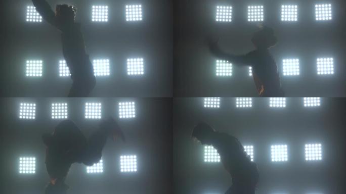 一个男舞者的剪影在工作室里跳霹雳舞、嘻哈、街舞，与世隔绝。在带有霓虹灯聚光灯的黑暗烟熏工作室拍摄。特