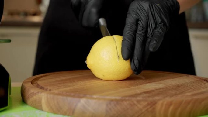 厨师拿着柠檬，用小刀轻动将成熟的水果切成两半。特写