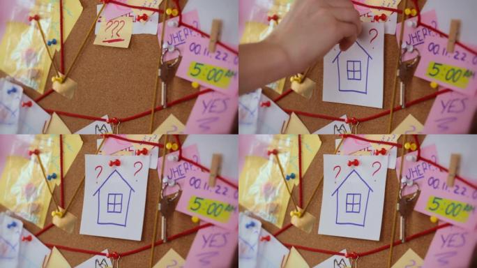 房地产搜索概念。有证据的侦探委员会的特写视图。在中间，女人的手别着一张带有房屋图标的白纸