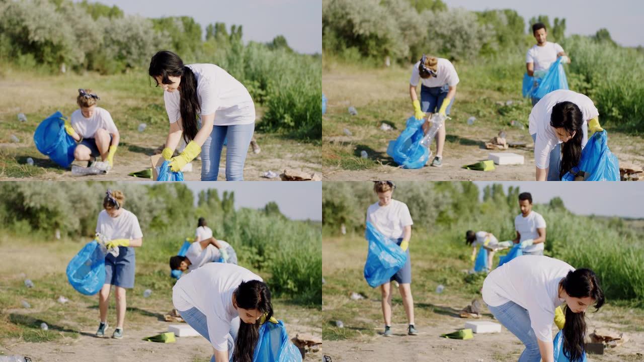 在湖边的志愿者小组清理垃圾并将垃圾收集在蓝色的塑料袋上，他们从海滩上整理垃圾