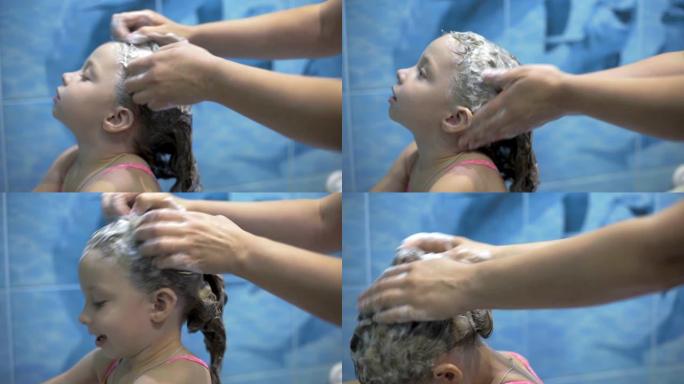 妈妈用婴儿洗发水洗小女儿的头，照顾孩子。