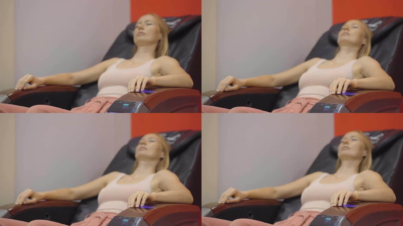 一个年轻女子坐在自动按摩椅上的手持照片。专注于手