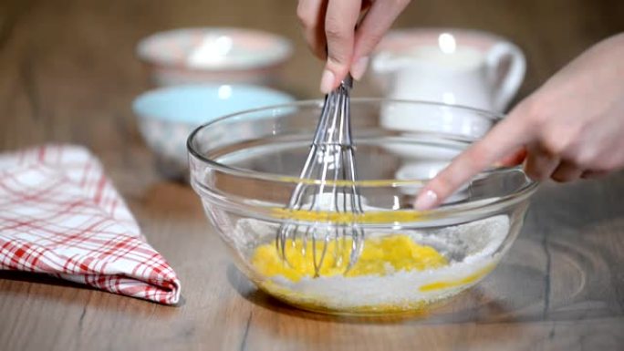 在玻璃碗里搅拌鸡蛋和糖。