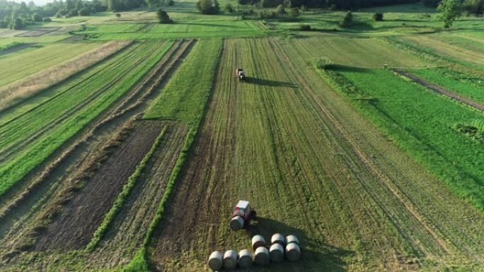 农业田间打捆干草拖拉机上的无人机观点-库存视频