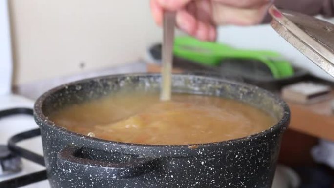 这个人正在做苹果果酱。用勺子在平底锅里搅拌。特写镜头。